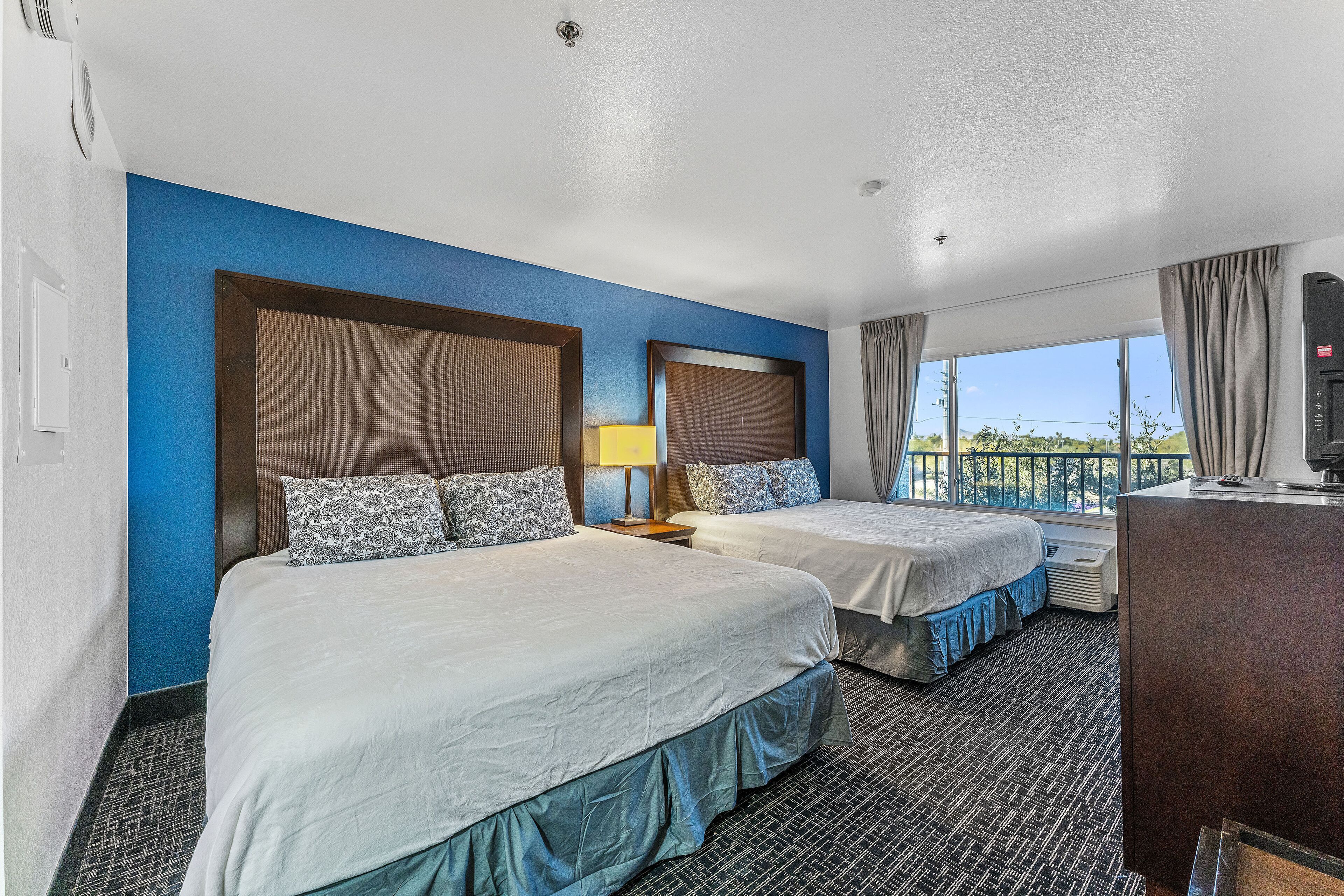 Een hotelkamer met twee bedden, een bureau en een groot raam met uitzicht.
