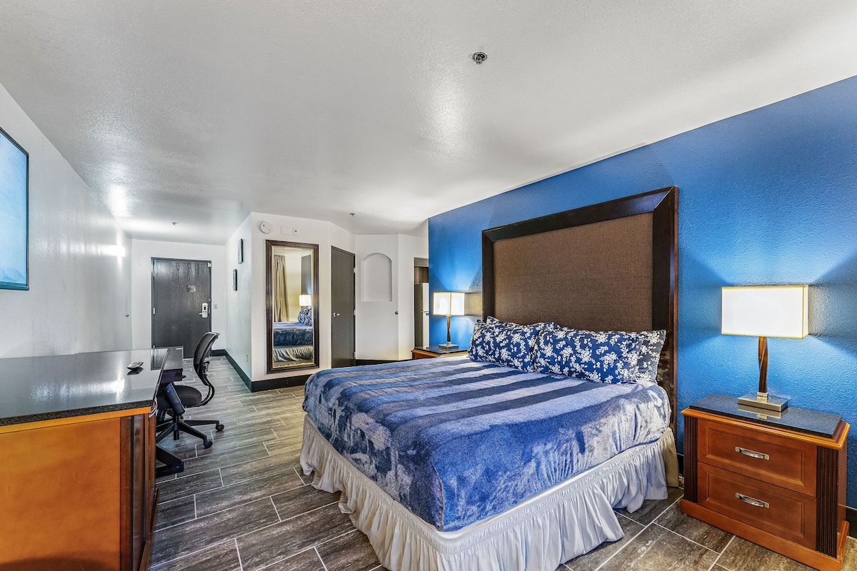 A hotel room with a large bed, a desk, and a chair.