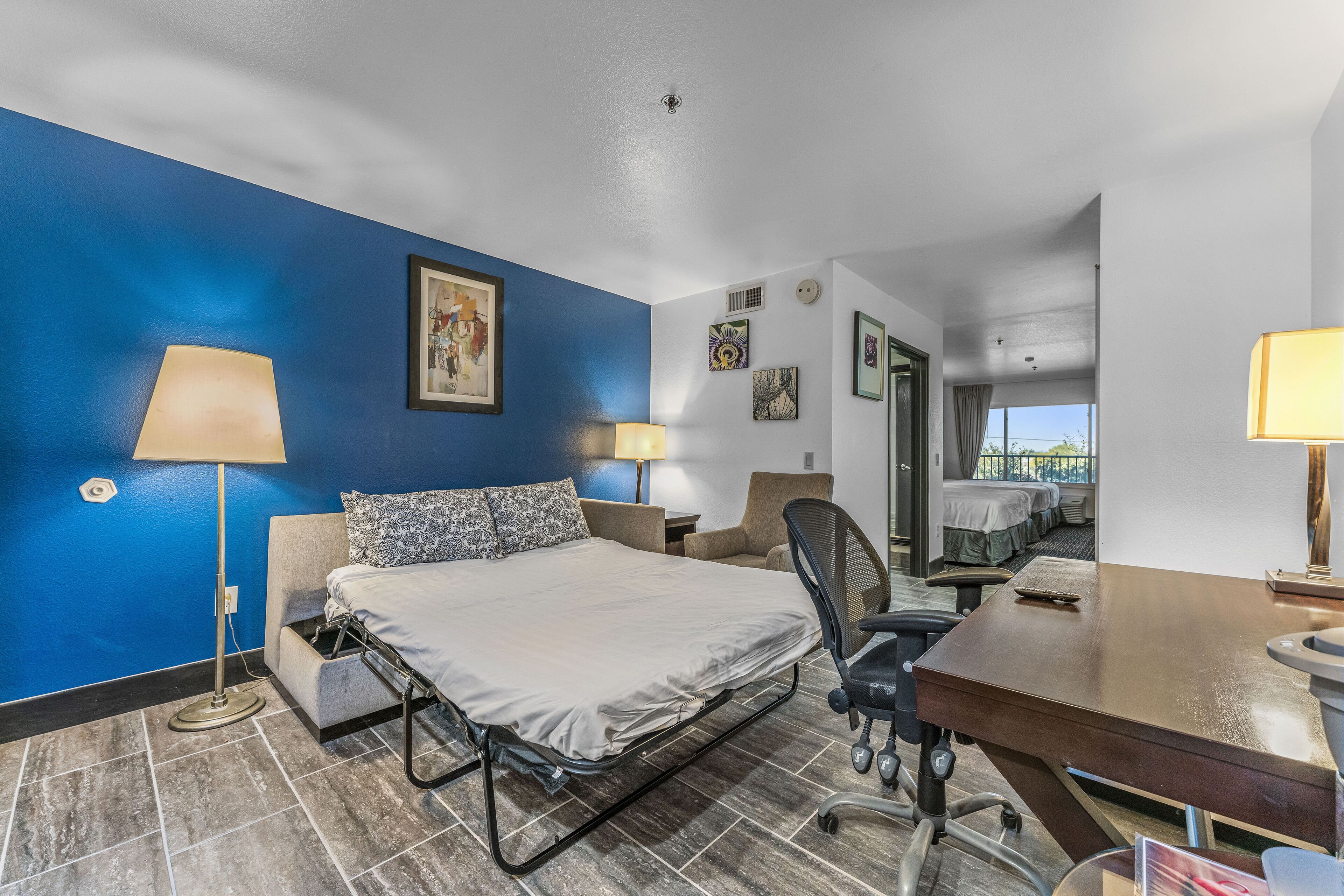 Une chambre d’hôtel comprenant un lit, un bureau, une chaise et deux lampes.