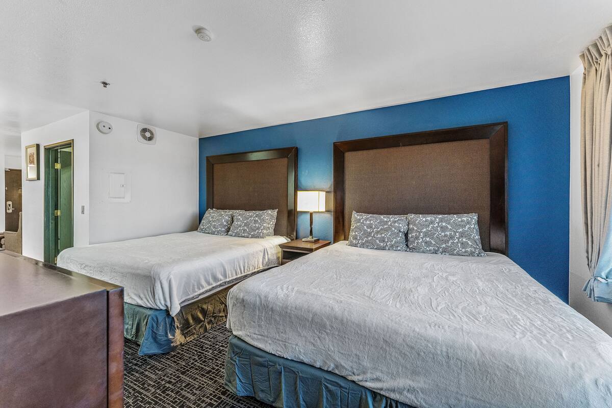A hotel room with two beds, a desk, and a chair.