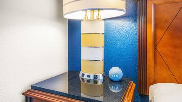 A modern bathroom with a black countertop, a white and gold lamp, and a digital clock displaying 1:15.