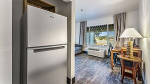 A modern kitchen with a built-in refrigerator, a dining area with a table and chairs, and a view through a window.