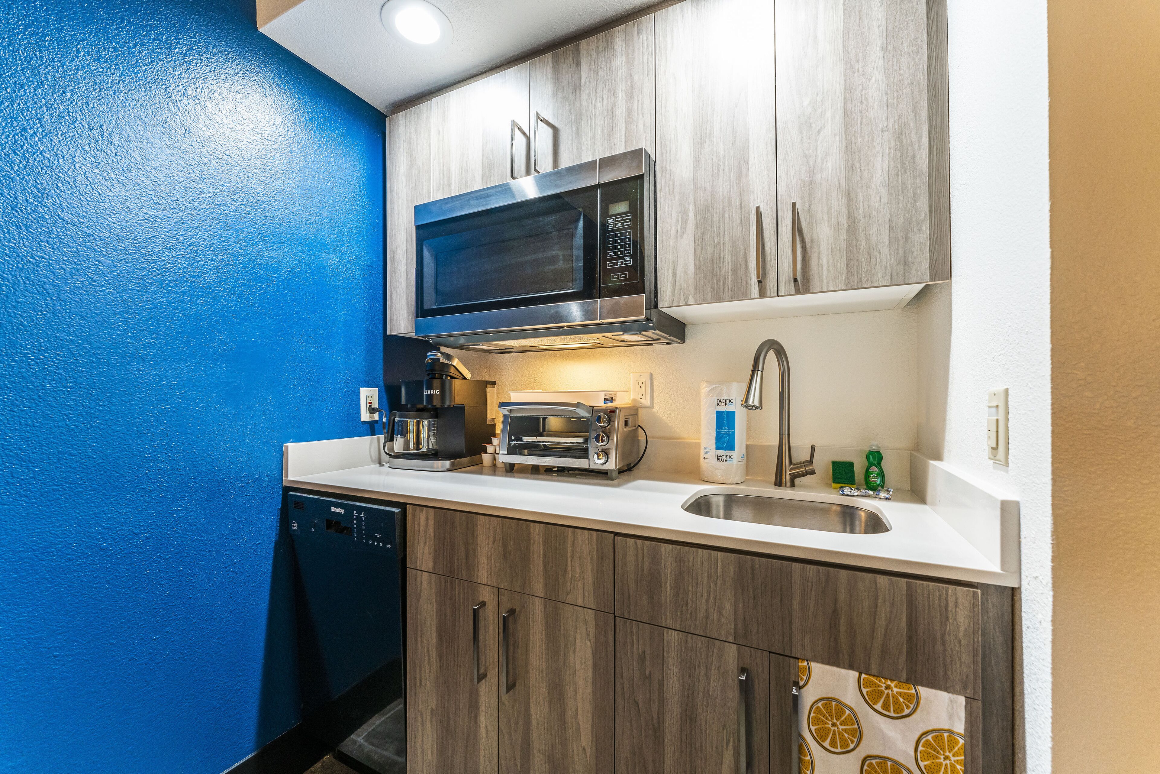 A compact kitchen with a microwave, toaster, and sink.