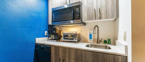 A compact kitchen with a microwave, toaster, and sink.