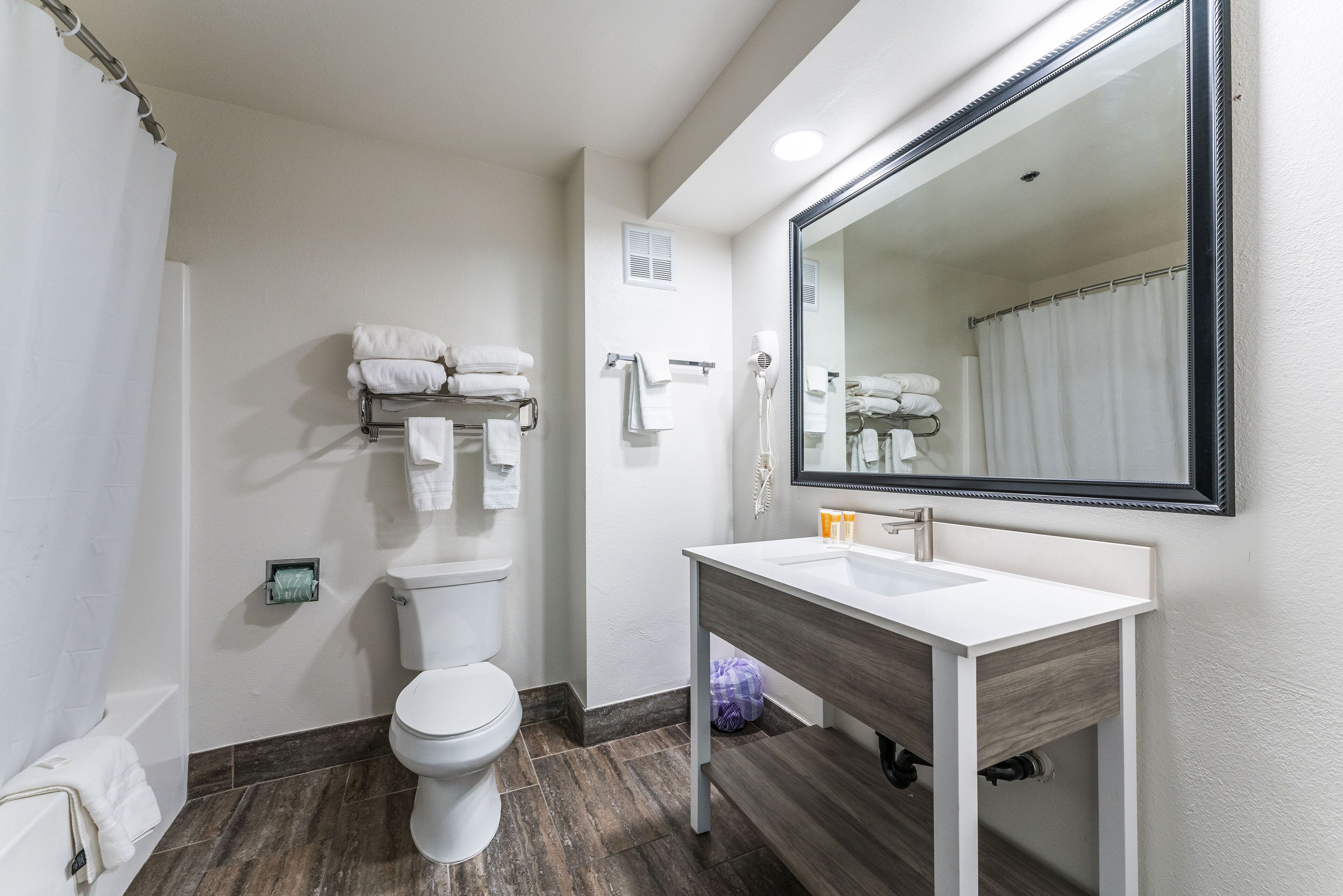 Un bagno moderno con un water bianco, un lavabo con specchio e un porta asciugamani.