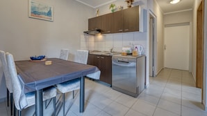 A modern kitchen with a dining table, chairs, and a dishwasher. - Radmila by Interhome (Krk/Šilo)