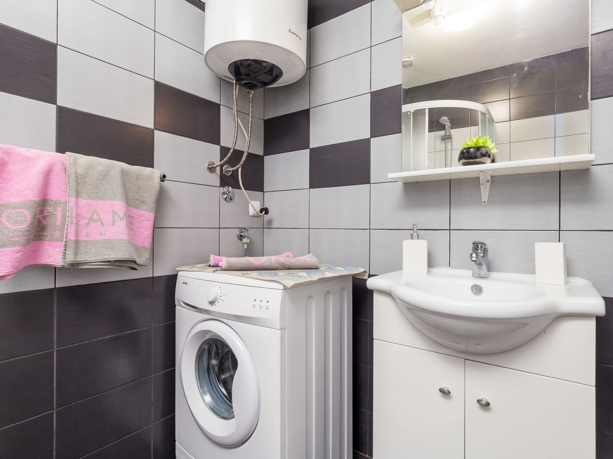 Une salle de bain moderne équipée d’un lave-linge, d’un lavabo et d’un porte-serviettes.