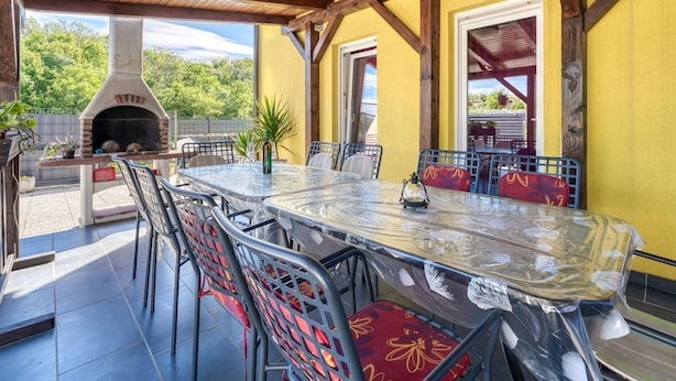 An outdoor patio with a brick oven, metal chairs, and a glass table. - Radmila by Interhome (Krk/Šilo)