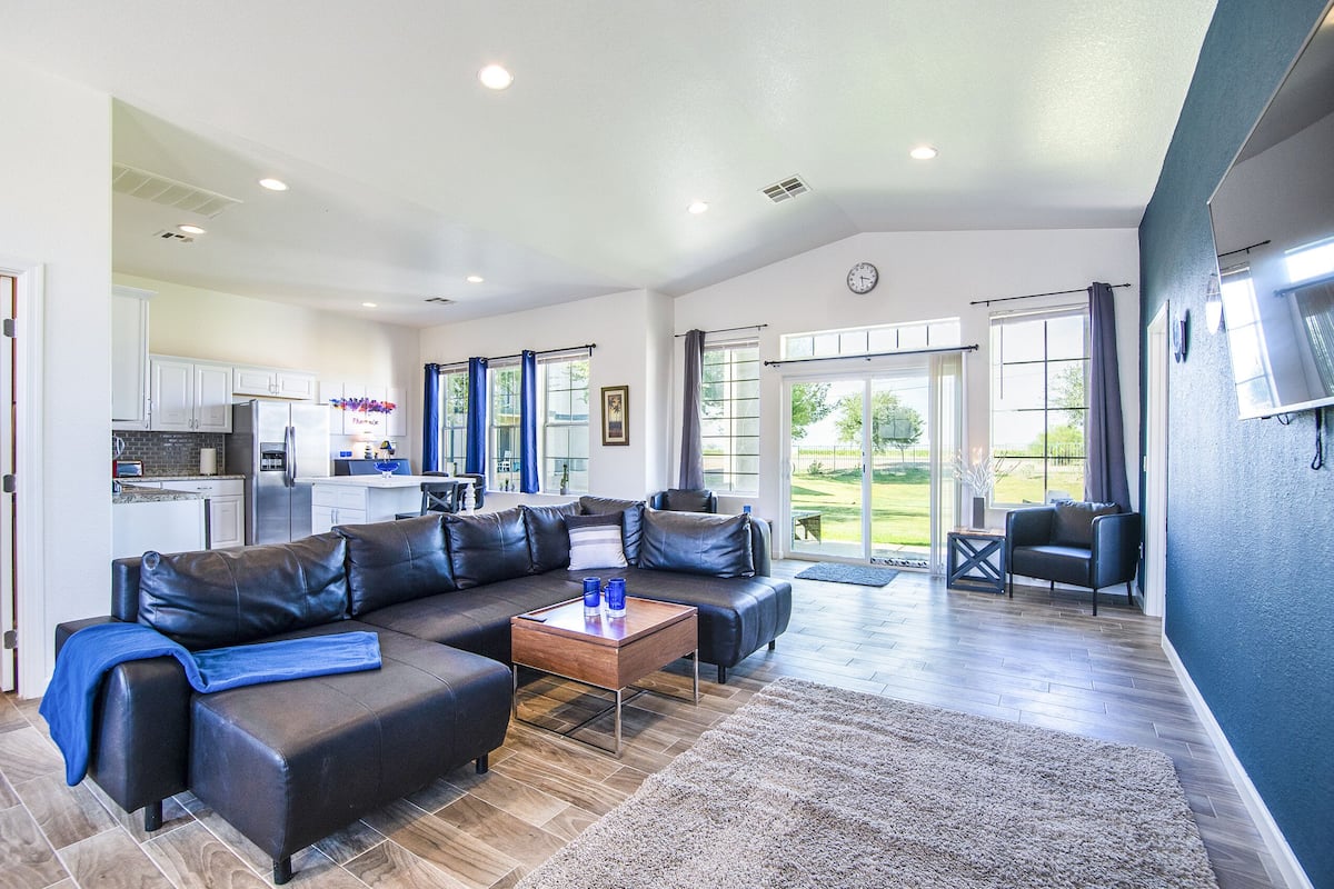 A spacious living area with a sectional sofa, a coffee table, and a view of the kitchen and outdoor patio.