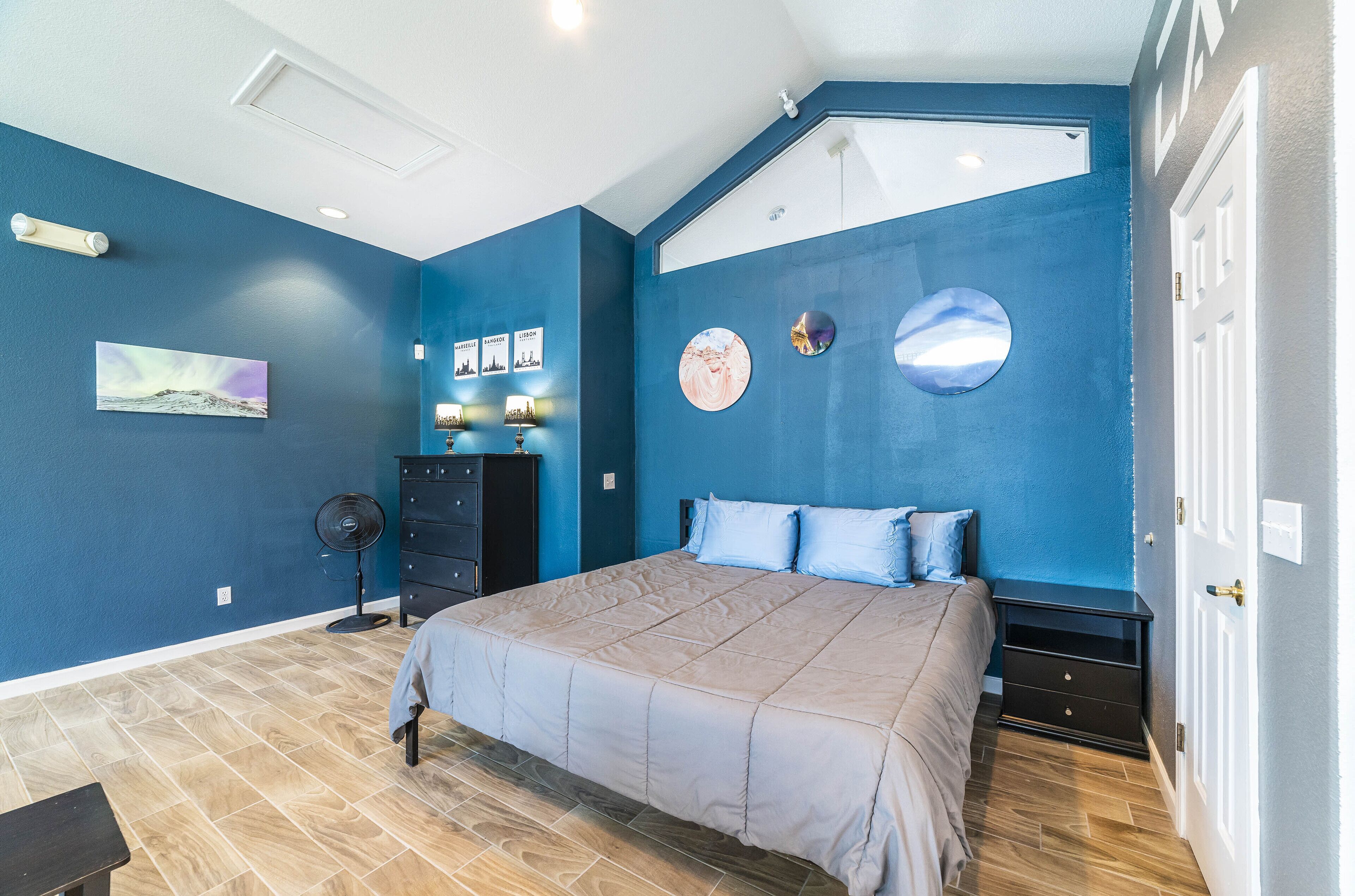 A bedroom with a bed, dresser, and wall art.