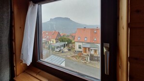 A window with a view of a mountain and residential buildings. - Vacation in nature - view of the Elbe Sandstone Mountains in Saxon Switzerland (Königstein)