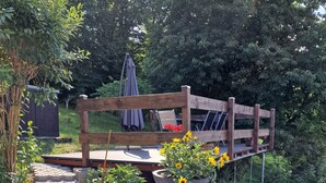 A wooden deck with a bench and a table, surrounded by a garden with a stone pathway. - Vacation in nature - view of the Elbe Sandstone Mountains in Saxon Switzerland (Königstein)