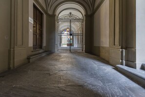 A corridor with a wrought iron gate, stone flooring, and arched ceilings.