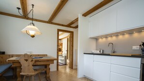 Una cocina moderna con armarios blancos, una mesa de comedor de madera y una lámpara colgante.