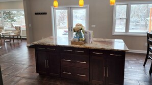 Una cocina con una isla grande, armarios de madera oscura y luces colgantes.