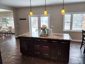 A kitchen with a large island, dark wood cabinets, and pendant lights.