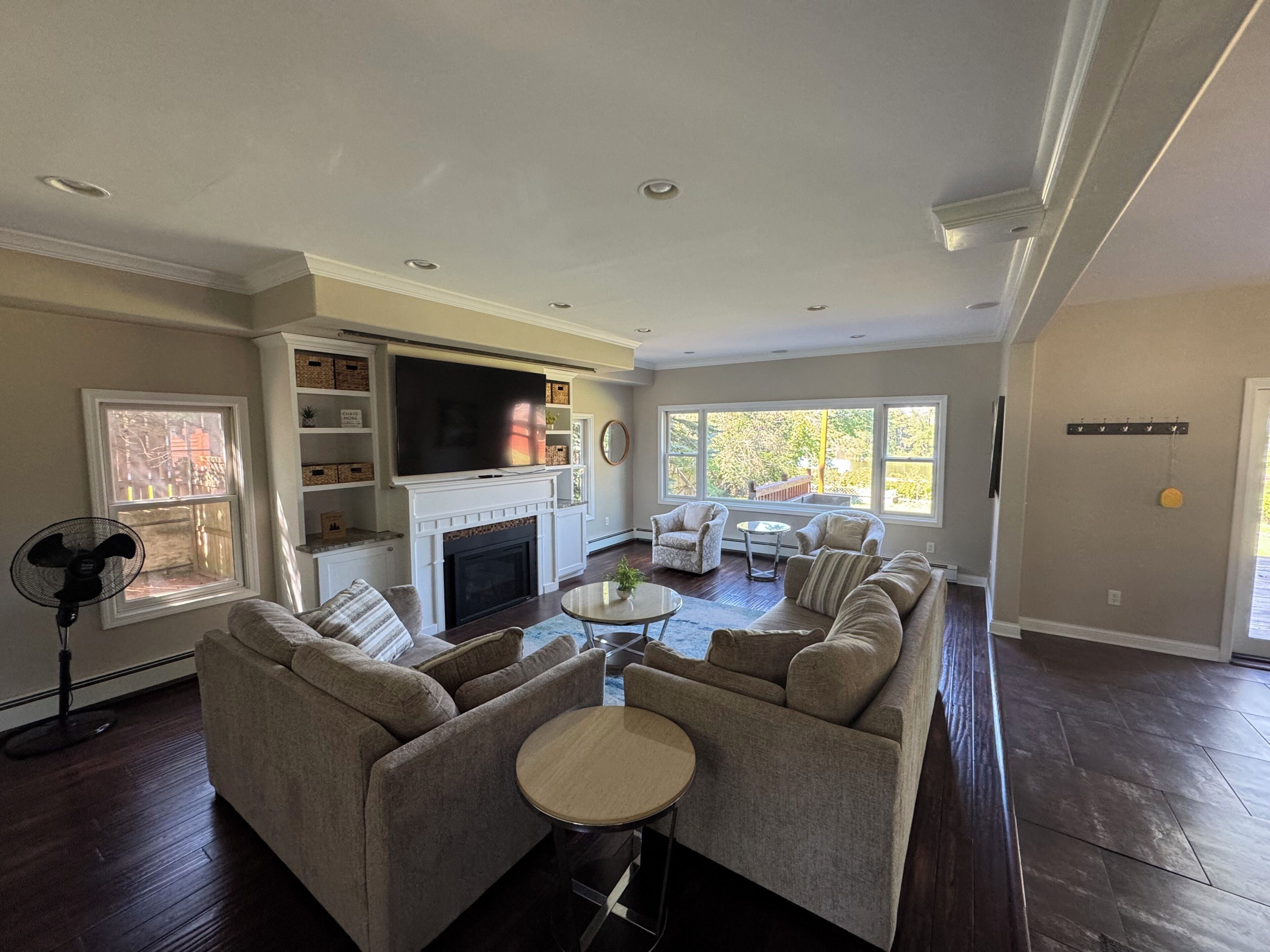 A living room with a fireplace, a large TV, a sofa set, and a dining area.