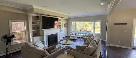 A living room with a fireplace, a large TV, a sofa set, and a dining area.