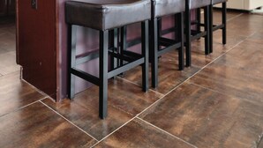 Una cocina con armarios de madera oscura, encimera de mármol y una isla central con taburetes de bar.