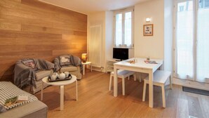 Ein gemütliches Wohnzimmer mit einer Couch, einem Esstisch und einem Fernseher.