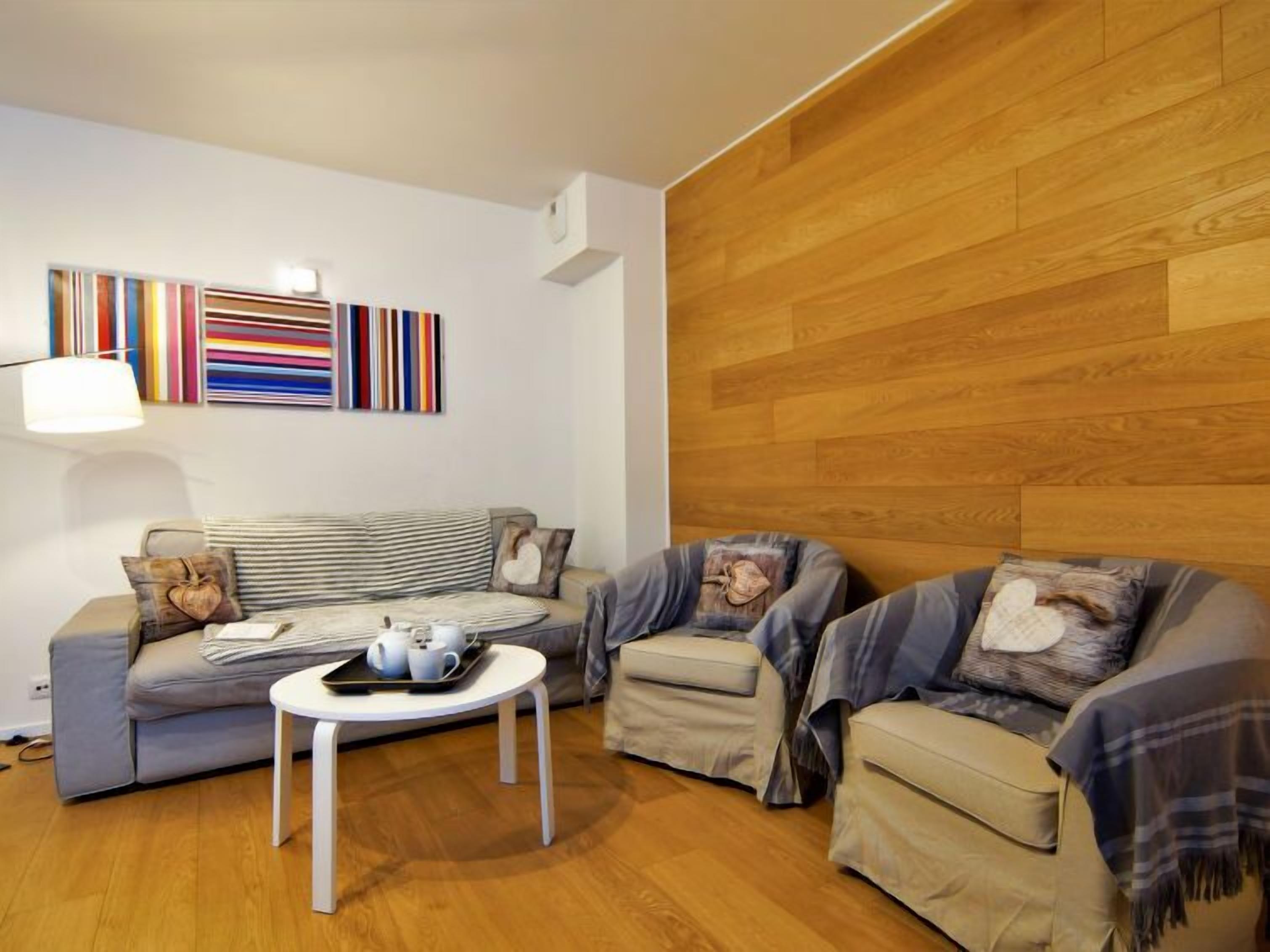 Un salon moderne avec un canapé, deux fauteuils, une table basse et un mur d’accent en bois.