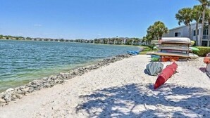 Une plage bordée d’une rangée de bateaux, avec un bâtiment visible au loin.