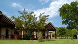 A building with a brick facade, a covered patio area, and a well-maintained lawn. - Greenway woods Self Catering unit no 9, WhiteRiver (White River)