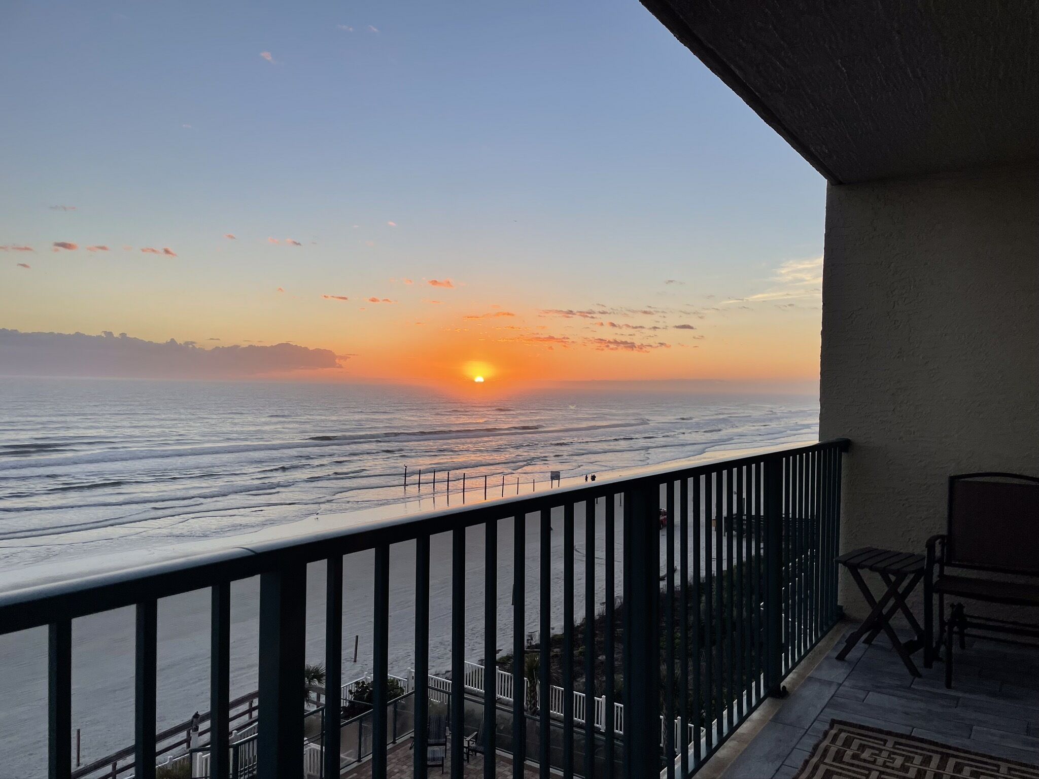 A balcony with a view of the ocean at sunset.