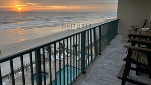Un balcón con vista a la playa y al océano al atardecer.