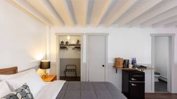 Un dormitorio con cama, lámpara de noche, armario y una pequeña zona de kitchenette.