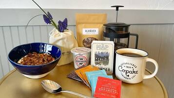 A breakfast setup with a bowl of cereal, a coffee mug, a thermos, a map, and some tea packets.