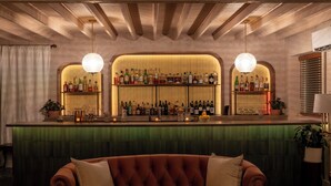 A bar area with a green counter, two pendant lights, and shelves stocked with bottles. - the Alander (Copake)