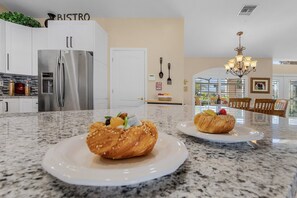 A kitchen with a stainless steel refrigerator, a granite countertop, and two plates with pastries.