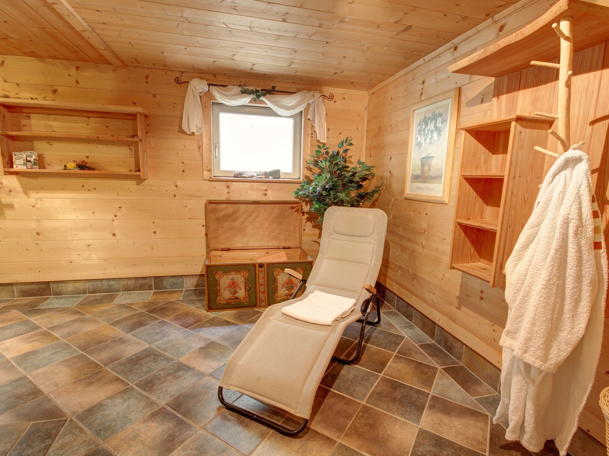 Una spa con stanza in legno, una sdraio, una finestra, una pianta in vaso e un porta asciugamani.