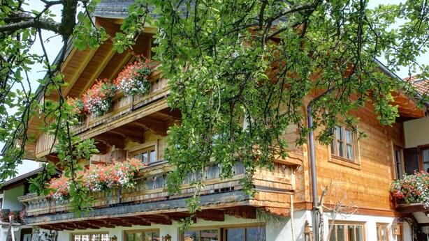 A wooden chalet with a balcony adorned with hanging flower baskets, outdoor seating, and large windows. - Vacation apartment Kienberg for 2 persons, 1 bedroom, balcony, 38 sqm, n. k. (Inzell)