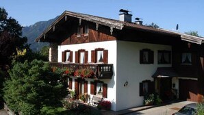 Een klassiek chalet met een houten balkon, witte muren en een berg achtergrond.