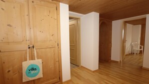 A wooden-paneled room with a wooden door, a white wall, and a wooden floor. - Charming holiday home near the ski resort (Kaltenbach)