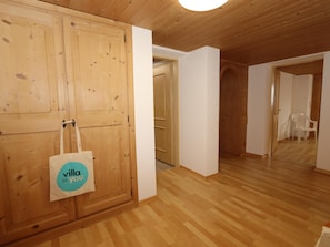 Um quarto com painéis de madeira, uma porta de madeira, uma parede branca e piso de madeira.