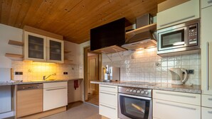 A modern kitchen with wooden ceiling, stainless steel appliances, and a tiled backsplash. - Charming holiday home near the ski resort (Kaltenbach)