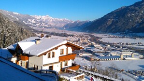 A mountain town with snow-covered buildings, a ski resort, and a clear view of snow-capped mountains in the background. - Charming holiday home near the ski resort (Kaltenbach)