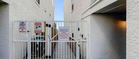 A gated entrance to a private residential community with security measures including a surveillance camera and warning signs.