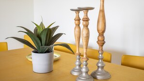 Une table à manger agrémentée d’une plante en pot et de deux chandeliers.