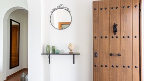 Une porte en bois avec une poignée en métal, un miroir rond et une étagère ornée d’objets décoratifs.