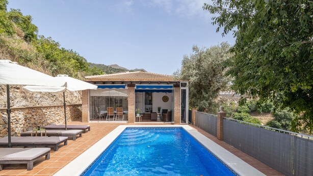 Une piscine avec des chaises longues, un patio couvert et une vue sur le paysage environnant.
