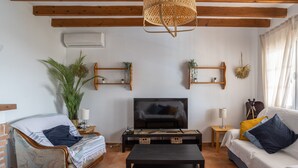 Un salon avec un canapé, une table basse, un téléviseur et une plante.