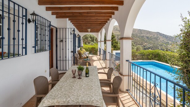 Une terrasse couverte avec une piscine, une table à manger et des chaises, offrant une vue sur un paysage magnifique.
