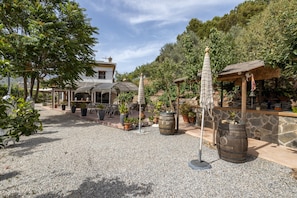 Un patio con mobiliario exterior, plantas en macetas y un muro de piedra.