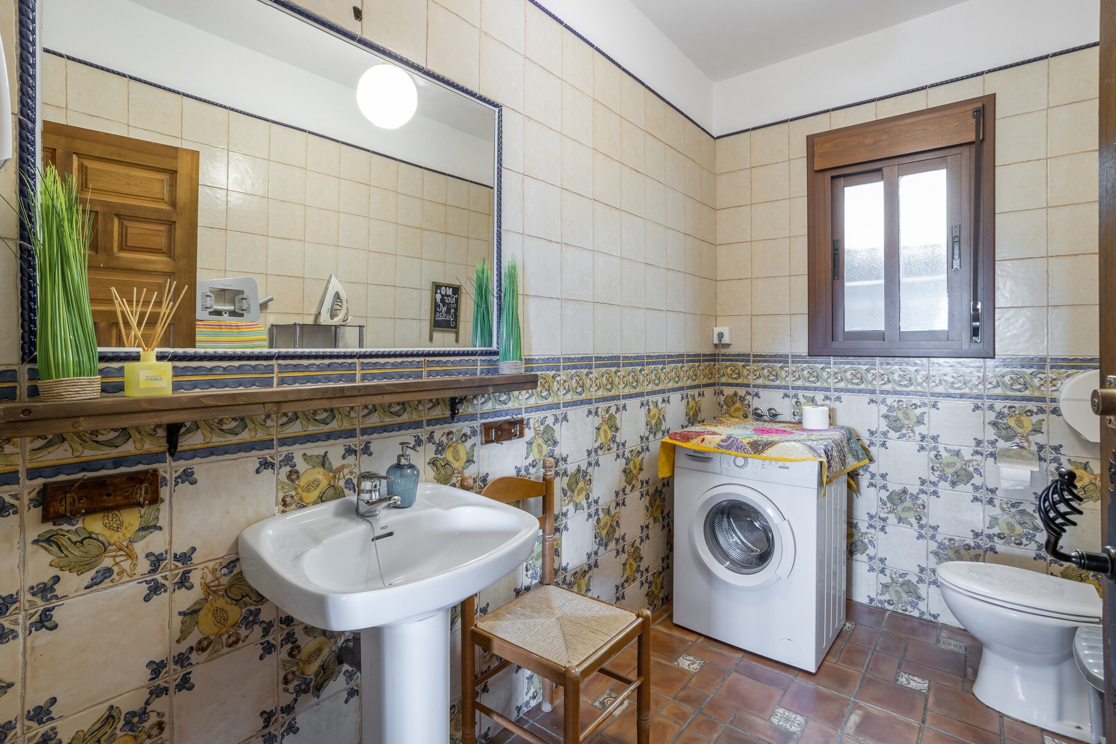 Une salle de bain équipée d’un lavabo, d’un miroir, d’un lave-linge, de toilettes et d’une fenêtre.