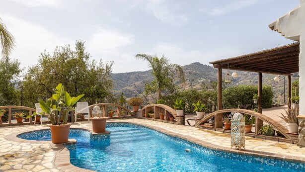A swimming pool with a stone border, surrounded by potted plants and outdoor furniture. - Holiday Home 'Finca Arrijana' with Mountain View, Wi-Fi and Air Conditioning (Sayalonga)