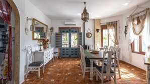A dining area with a wooden table and chairs, a mirror, and a hanging light fixture. - Holiday Home 'Finca Arrijana' with Mountain View, Wi-Fi and Air Conditioning (Sayalonga)